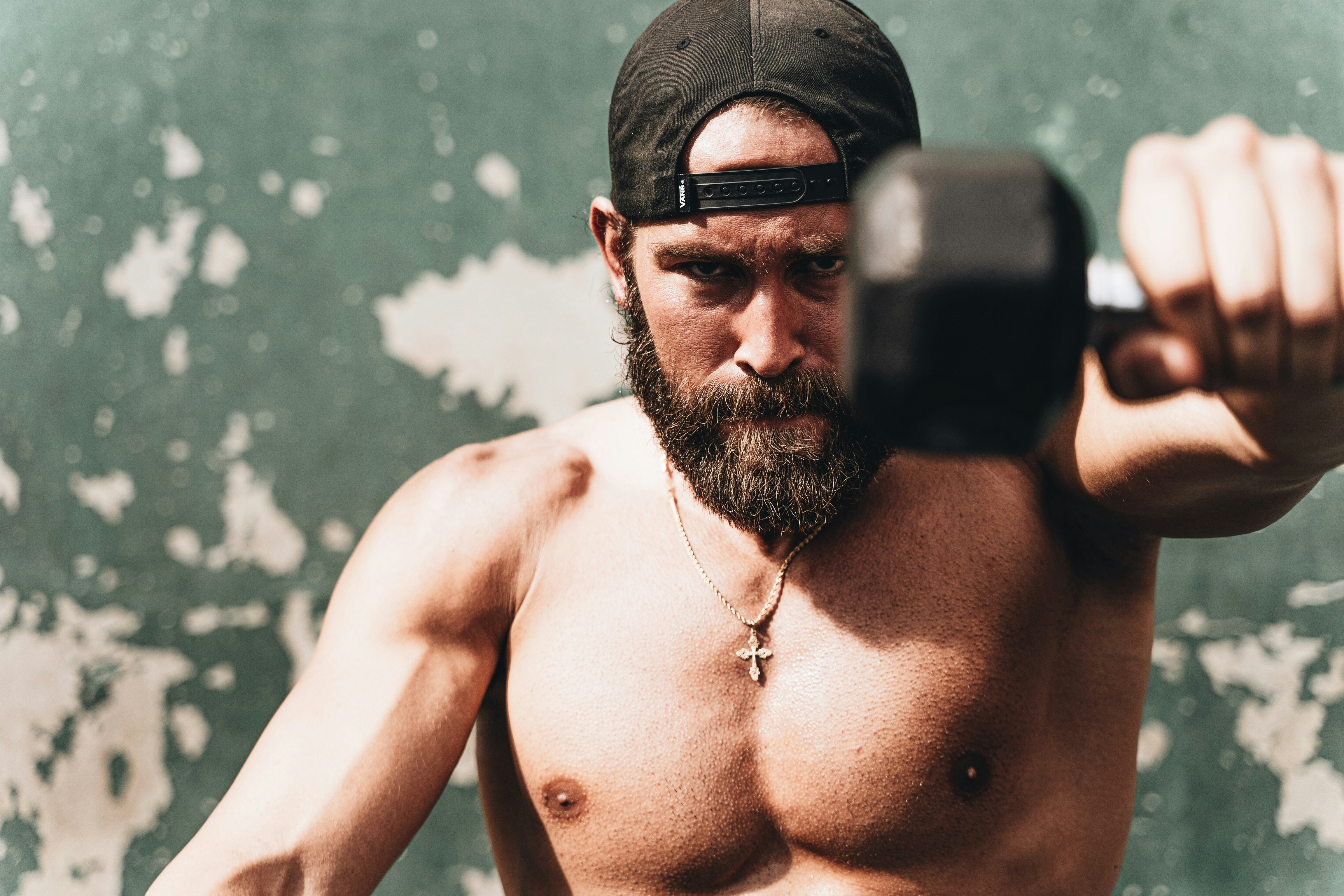 Man with healthy testosterone and a beard, exercising with dumbbells